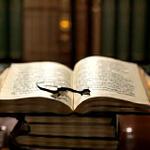 A stack of open books with a magnifying glass over them, representing in-depth research and learning, specifically on stress management.